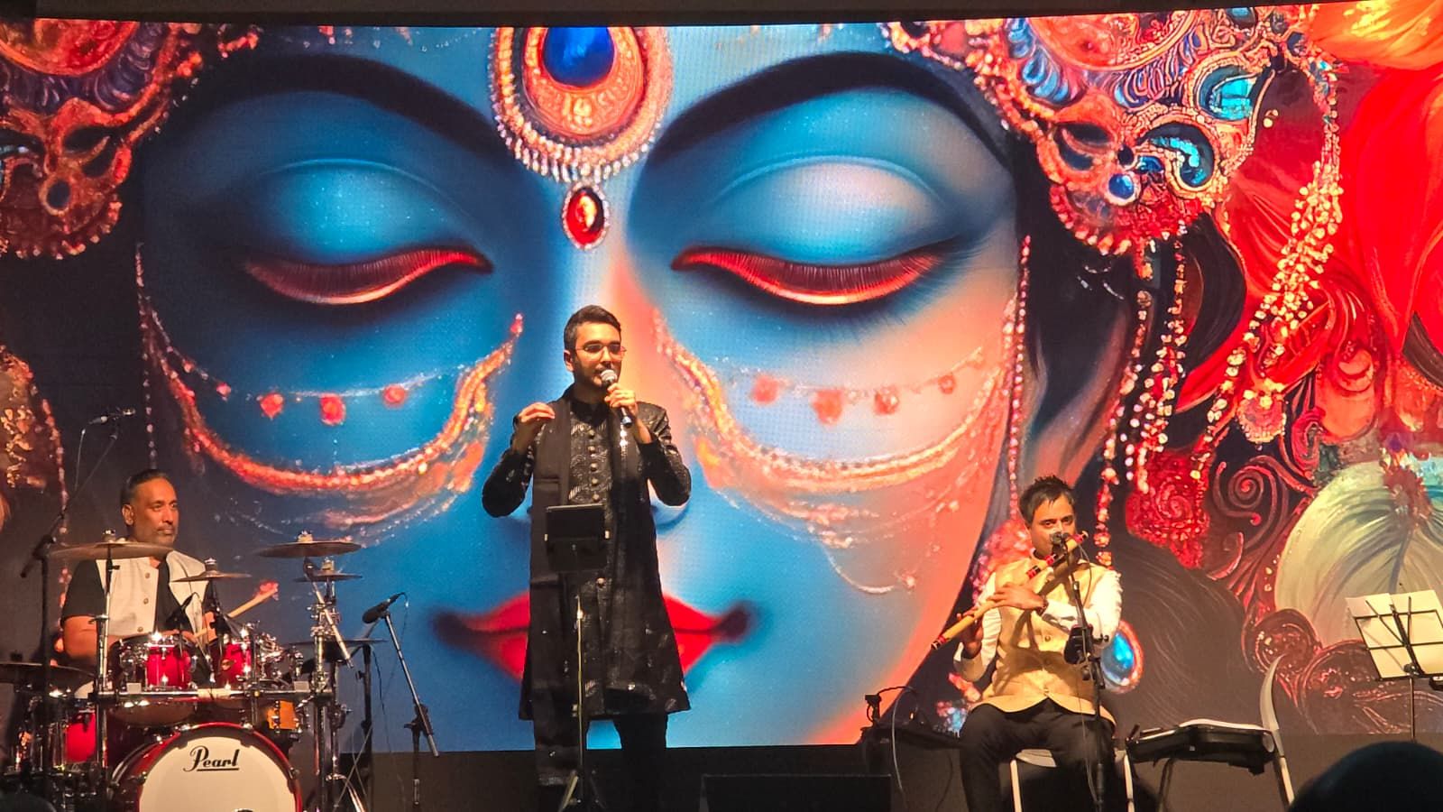 Priyesh Shah mid-song between the drummer and the bansuri player, the Goddess on screen behind