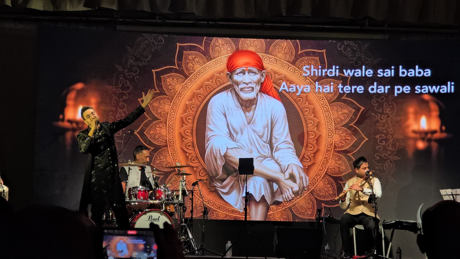 Shirdi Sai Baba on the screen as Priyesh Shah sings with arms outstretched
